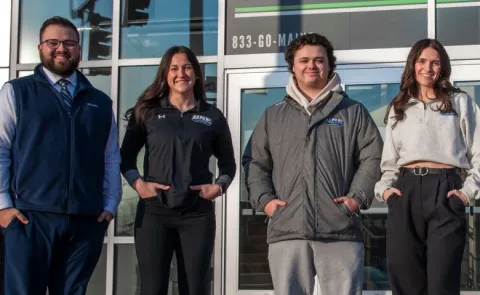 UNE business students pose in front of the Cross Insurance Arena in Portland