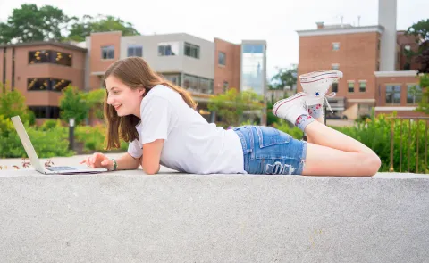 A UNE student works on her laptop outside the Danielle N. Ripich Commons