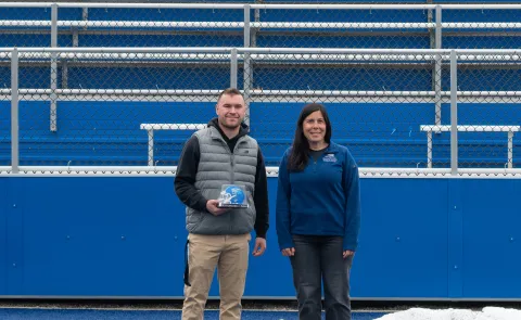 UNE student Ty LeBlond poses with professor Aimee Vlachos at UNE's football stadium