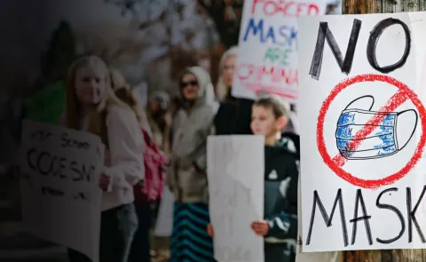 A graphic depicts a protest with anti-mask signs