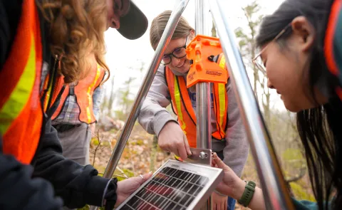 UNE students assemble components of a weather station in UNE's research forest