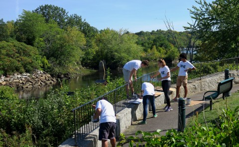 UNE volunteers paint the fence at Mechanics Park in Biddeford as part of UNE's Day of Service.