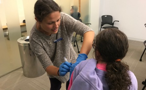 Nursing student Elizabeth Alvin administers a flu shot to a health fair visitor