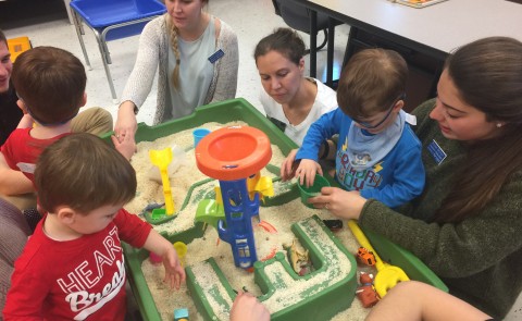 Occupational Therapy and Physical Therapy students engage with children at the sand table during Playgroup
