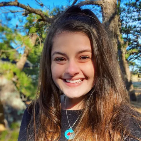 Dominique Mellone stands in front of a tree smiling at the camera