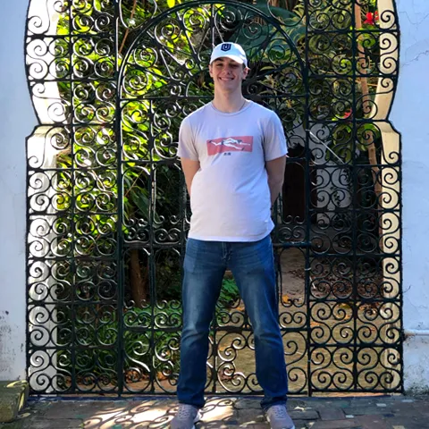 Devin Jozokos stands in front of a decorated metal doorway in Morocco, smiling at the camera