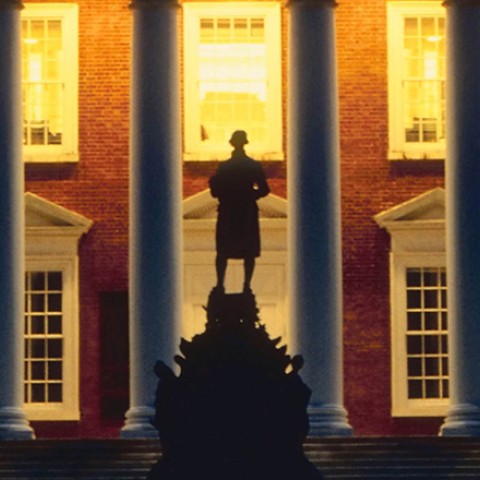 Photo of a statue silhouetted against a college building
