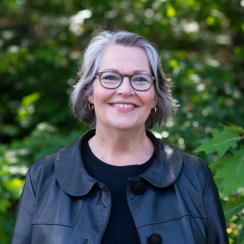 Portrait of Karen Houseknecht smiling against trees