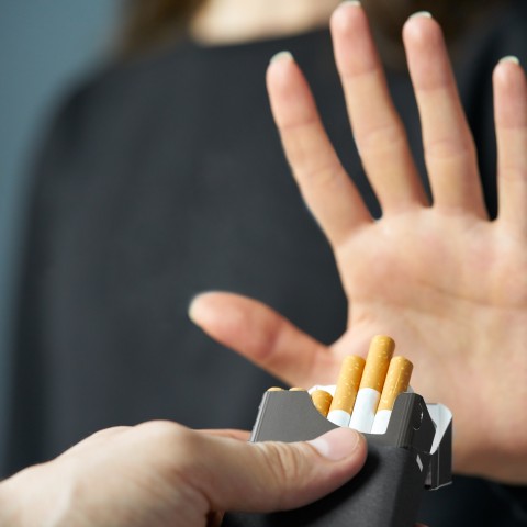 Stock image of a person raising their hand "no" to an offer for a cigarette
