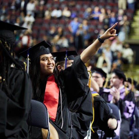 A student points to the crowd during the 187th Commencement ceremony at the Cross Insurance Arena in Portland