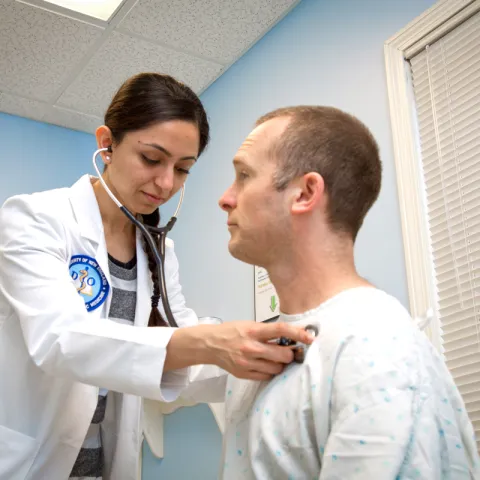 A UNE medical student listens to the heartbeat of an older adult during a health screening