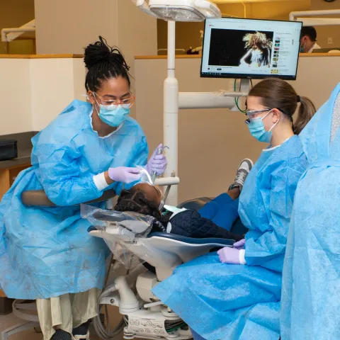 UNE dental students engage with a child patient in the Oral Health Center