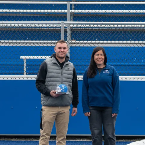UNE student Ty LeBlond poses with professor Aimee Vlachos at UNE's football stadium