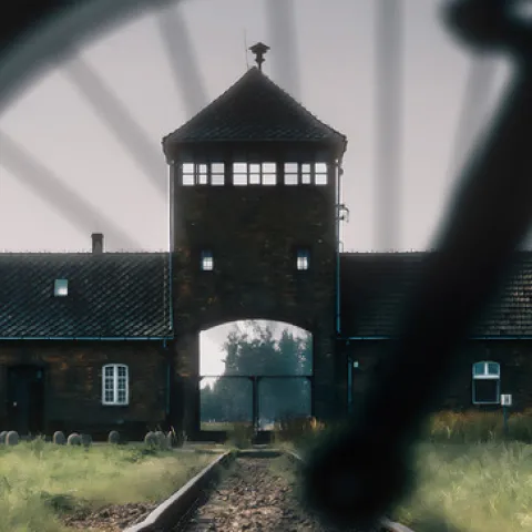 A view of the entrance to Auschwitz-Birkenau as seen through the spokes of a bike wheel
