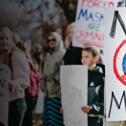 A graphic depicts a protest with anti-mask signs