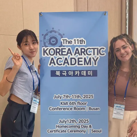 Shauna and her roommate pose in front of a Korea Arctic Academy banner