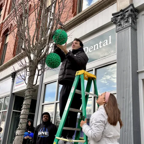 UNE students hang holiday lights, help provide holiday cheer in downtown Biddeford 