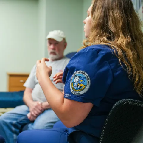 Close up mage with a nursing student's scrubs with UNE insignia