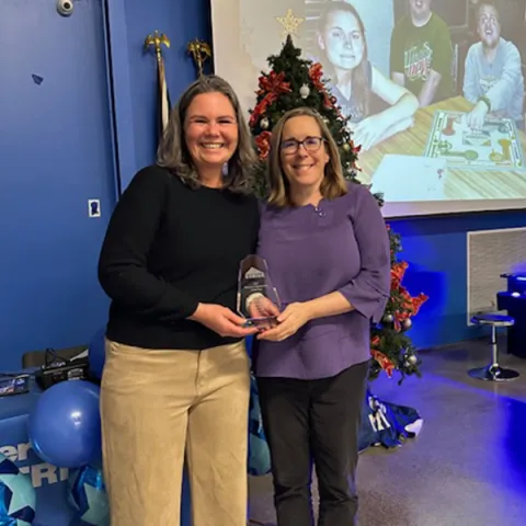 Two UNE faculty members (Jessica Walton and Erin McCall) pose with an award trophy