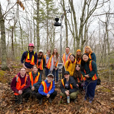 Cropped group photo of UNE students with a forest weather station