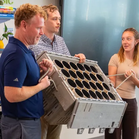 Marine science students present a green crab enclosure