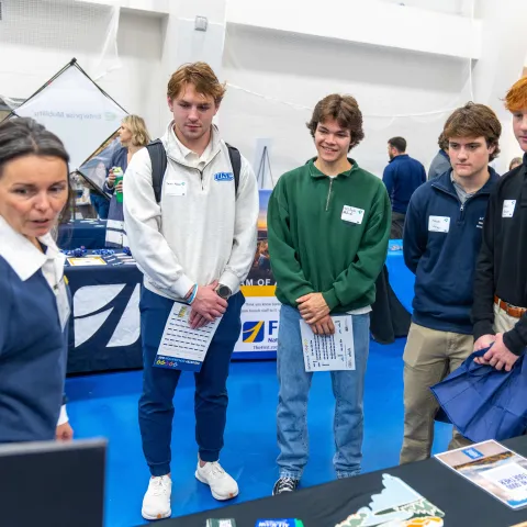 A group of male students speaks with a job recruiter