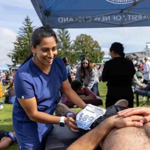 A UNE medical student evaluates a runner after a marathon